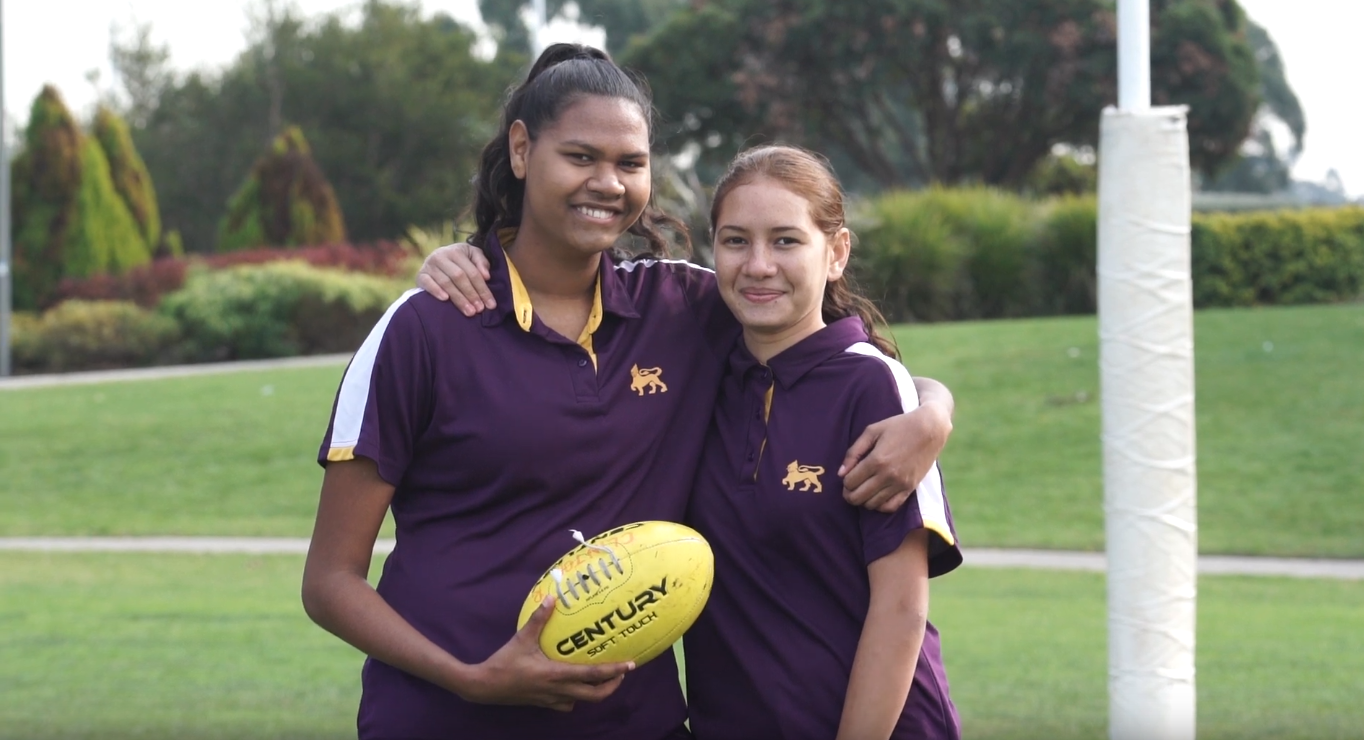 Two senior school girls smiling with their arms around eachother